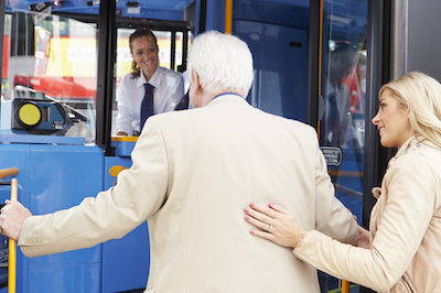 Woman Helping Senior Man To Board Bus