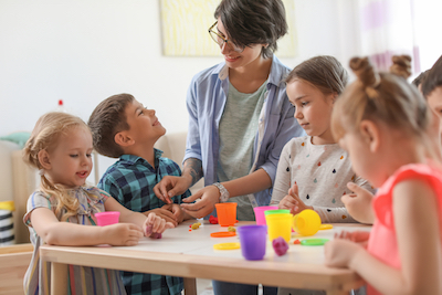 Young woman playing with little children indoors