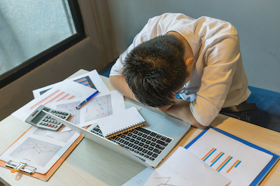 Stressed businessman fall asleep on the messy office desk