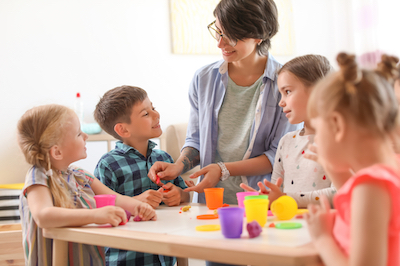 Young woman playing with little children indoors