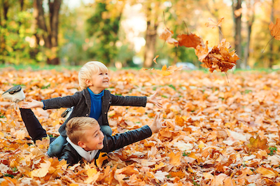 Cute children playing and laughing on autumn walk. Happy brothers throwing autumn leaves outdoors. Autumn vacation. Fashionable kids in park. Kids fashion. Boys playing with leaves.