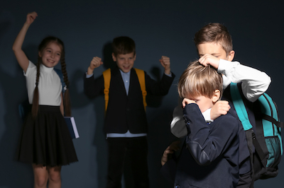 Little boy bullying his classmate on dark background