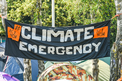 CARDIFF, WALES - JULY 2019: "Climate Emergency" banner hung between trees in a makesfit campsite in Cardiff city centre as part of the climate change protest by Extinction Rebellion.